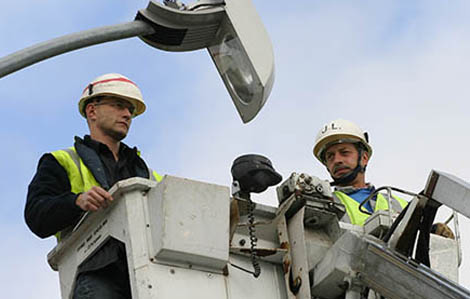 Cete photo représente des employers de la ville de Marmande qui réparent un lampadaire sur une nacelle