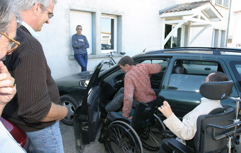 Cette photo représente un travailleur handicapé montant dans sa voiture